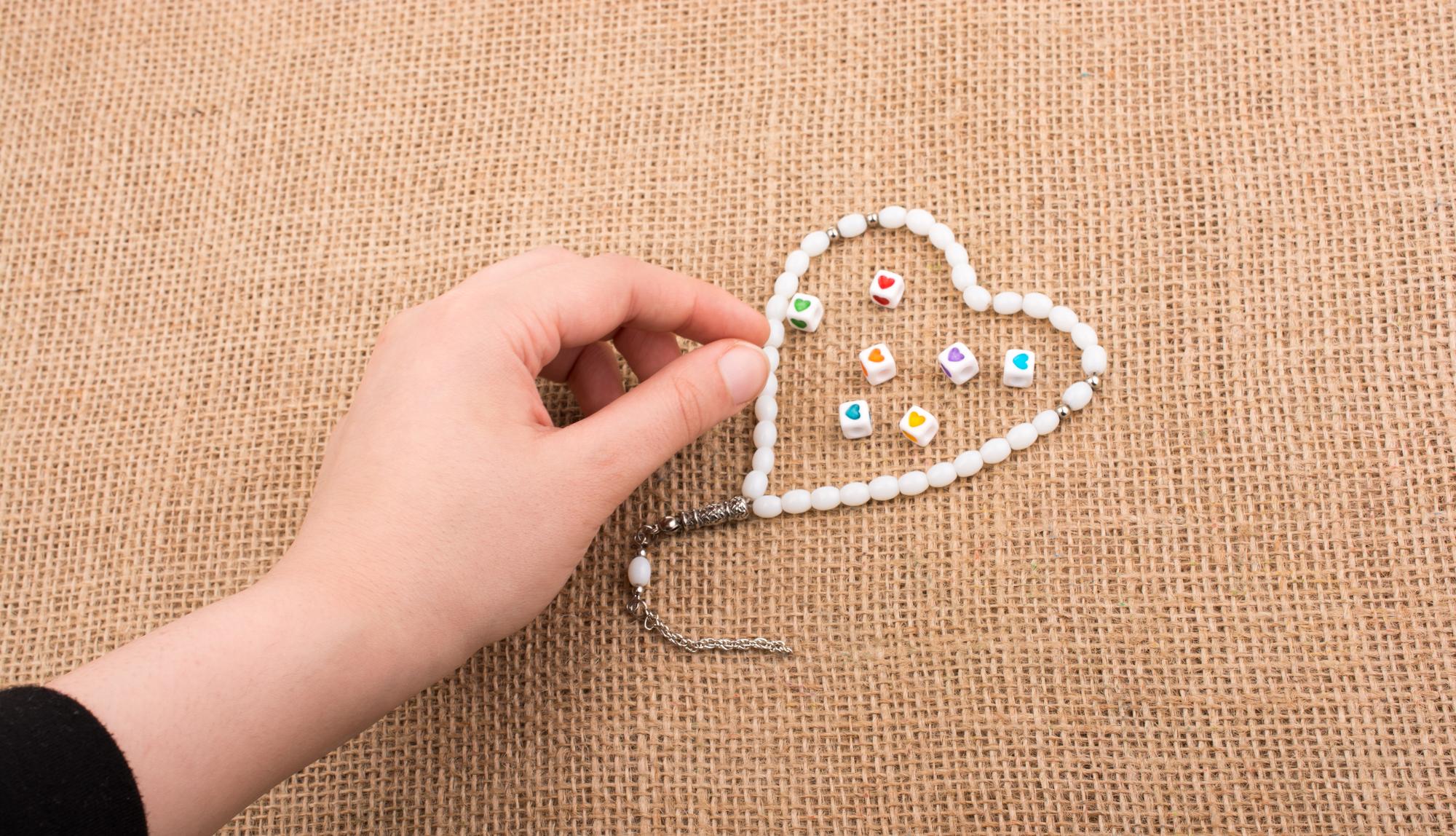 hands stitching beads into embroidery